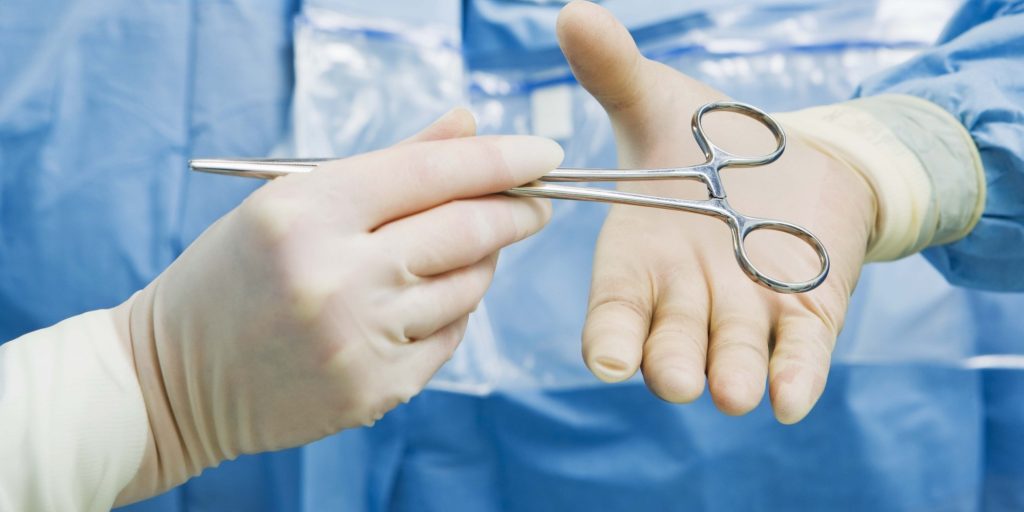 Nurse handing instrument to surgeon